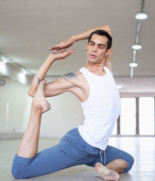 Man performing a controlled strength exercise with a focused expression in a dark, minimalist setting.